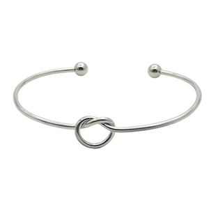 Detail of silver-tone knot cuff bracelet with ball ends and minimalist metal design