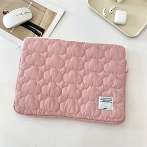 Detailed close-up of pink cloud quilted laptop sleeve on a minimalist desk workspace
