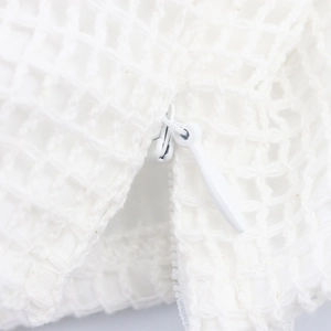 Gros plan sur un crop top en résille blanche avec fleurs 3D et fermeture éclair robuste