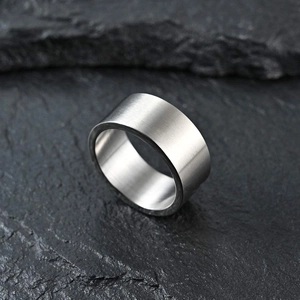 Detail of 10mm matte brushed silver titanium steel ring on black rock background