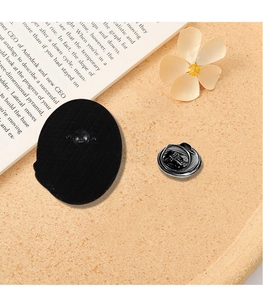 Detail view of black oval badge back component and silver metal butterfly clutch fastener