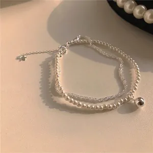Elegant double-layered bracelet with white pearls and silver bead pendant on beige leather