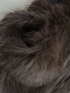 Macro texture of dark brown faux fur vest showing soft and fluffy synthetic fibers