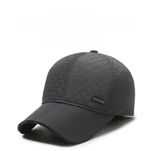 Detail of grey diamond-quilted baseball cap with ear protection and fashion metal badge