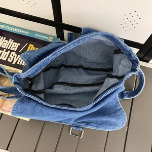 Vue de dessus d'un grand sac bandoulière en denim bleu avec boucle en métal et fermeture