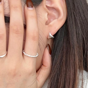 Detail shot of silver geometric triangle stud earrings and twisted rope ring on model