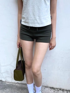 Outdoor view of women's dark green high waist fitness yoga shorts with a knitted t-shirt
