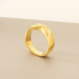 Macro shot of 18K gold wave ring with high-polish finish on a brushed pedestal