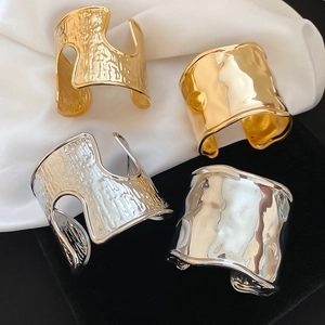 Detail of wide metallic textured open bangles in gold and silver finishes on silk