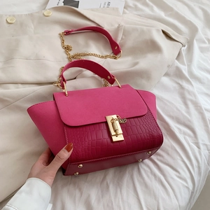 Detail of fuchsia winged bag featuring crocodile pattern leather and gold twist lock