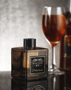 Close-up of amber glass diffuser bottle with black cap and elegant label on dark background