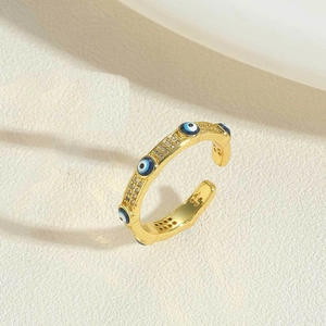 Macro shot of 14K gold plated Evil Eye open ring with blue stones on beige fabric