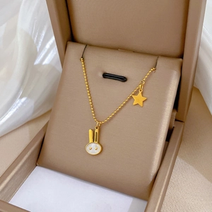 Golden rabbit and star pendant necklace on white satin inside a beige jewelry box