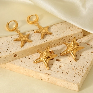 Detailed macro of gold starfish earrings with textured surface on natural stone base