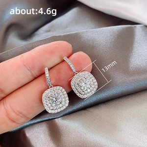 Handheld view of silver square double halo earrings with cubic zirconia and dimensions