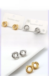 Detailed close-up of polished stainless steel twisted knot stud earrings in gold and silver