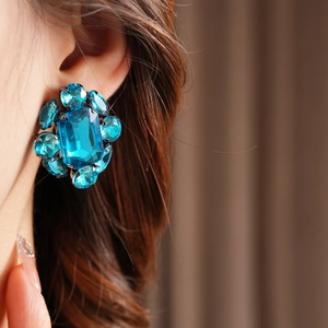 Gros plan d'une boucle d'oreille flocon en pierres bleues sur un modèle avec base argentée