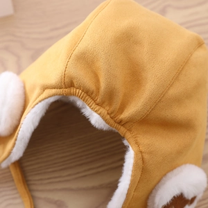 Detail of baby winter trapper hat showing soft white faux fur lining and plush yellow fabric