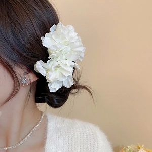 Elegant white fabric flower hair pin styled on a woman's hair bun with side view