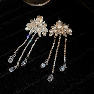 Macro shot of silver flower earrings with long crystal tassels and teardrop pendants