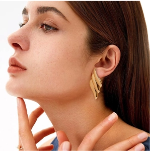 Close-up of model wearing chunky 18K gold plated earrings with irregular wavy texture