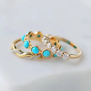 Macro shot of three stacked rings featuring turquoise, twisted gold band and cubic zirconia