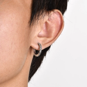 Macro shot of vintage silver earring featuring intricate cross floral embossed pattern