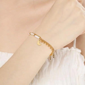 Double-layered gold stainless steel bracelet with moon, star charms and white beads on wrist