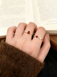 Detailed close-up of 18k gold plated vintage rings with red hearts and crystals on fingers