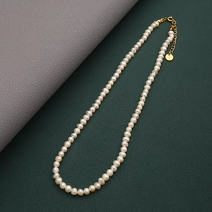 Dettaglio macro della collana di perle naturali con chiusura dorata e catena di estensione
