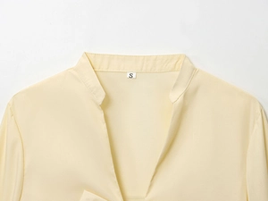 Detail of the V-neck stand-up collar and woven texture on this apricot long sleeve shirt