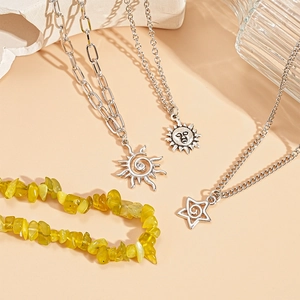 Silver celestial layered necklace set with sun and star pendants on a warm textured backdrop