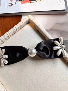 Détail d'une pince à cheveux en satin noir ornée d'une fleur de perles élégante