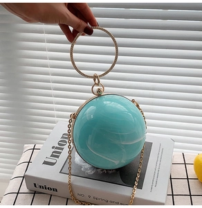Detail of turquoise marble acrylic ball clutch with rhinestone metal ring handle