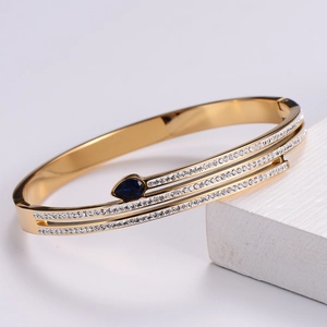 Detail of gold layered bracelet featuring a blue pear-cut gemstone and cubic zirconia