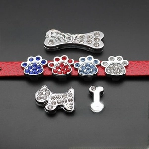 Macro shot of 10mm rhinestone paw and bone charms on a red leather wristband strap