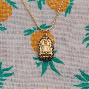 Golden Buddha pendant necklace with black zircon inlay on a sleek snake chain