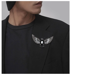Detail of vintage eagle brooch with black gemstone pinned to a men's black blazer