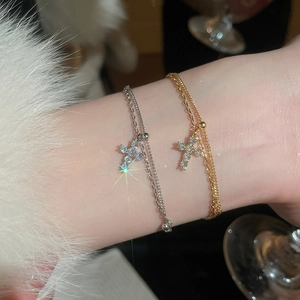 Detail of delicate gold and silver cross bracelets with cubic zirconia on a wrist