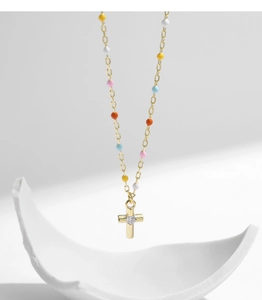 Detail of s925 silver gold necklace featuring colorful beads and a stone-set cross