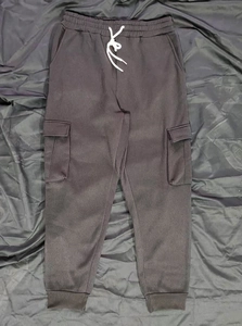 Detail showing elastic waistband with white drawstring and pocket on black cargo pants