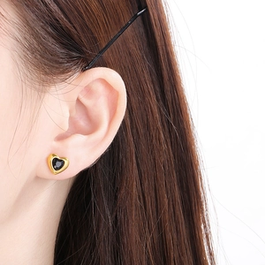 Gros plan détaillé d'une boucle d'oreille cœur en pierre noire et acier inoxydable doré 18k