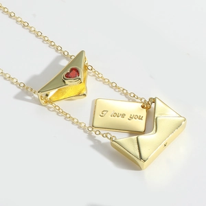 Macro view of gold envelope necklace with red heart zircon and I love you engraving
