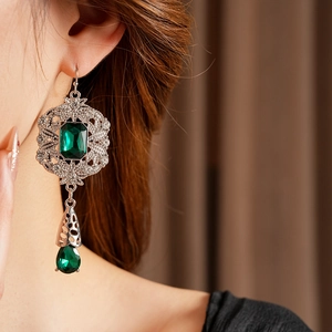 Close-up of vintage Baroque emerald drop earrings with silver metal and green crystals