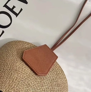 Close-up of woven straw hat texture with brown leather pentagon patch and strap