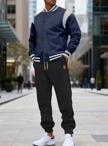 Detail of navy blue baseball jacket with grey sleeves and matching black joggers
