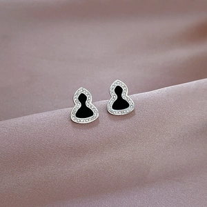 Macro view of silver gourd stud earrings with black center and sparkling white zircons