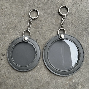 Detail van ronde grijze lederen badgehouder sleutelhanger op stenen ondergrond