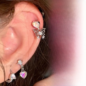 Detail of titanium steel stud earrings featuring butterfly and opal heart charms