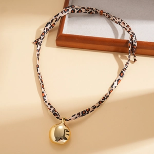 Détail du cordon léopard avec pendentif sphérique doré et perles en bois naturel